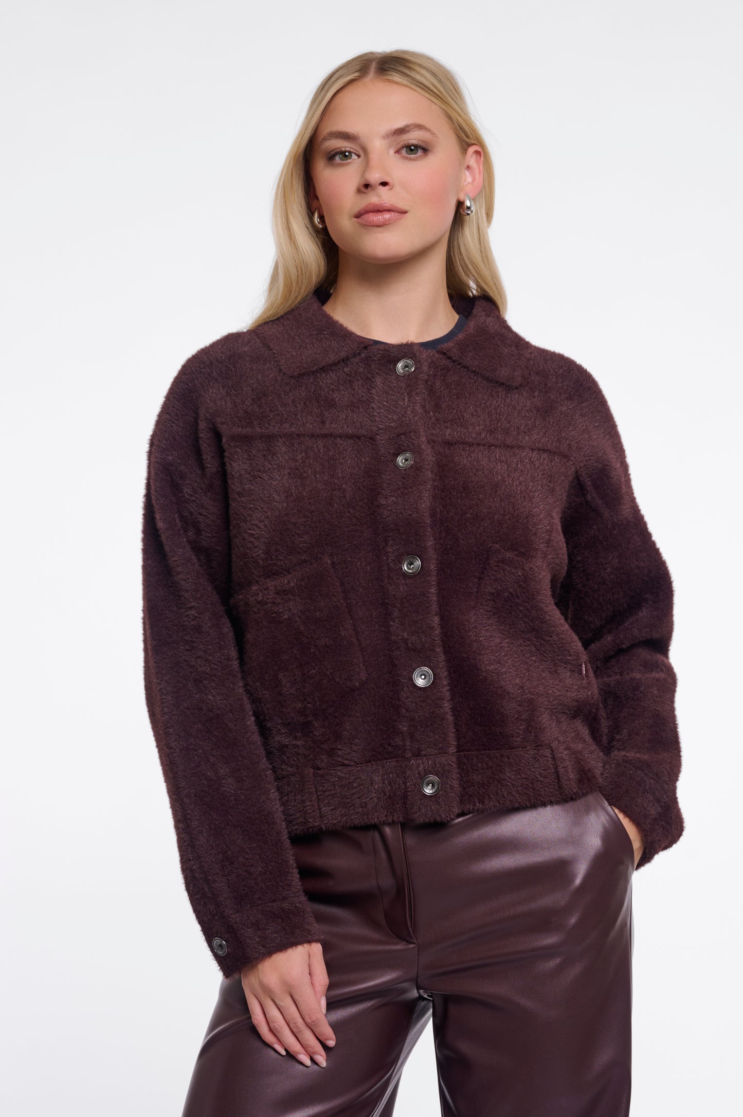 Woman wearing a brown jacket and pants on a white background
