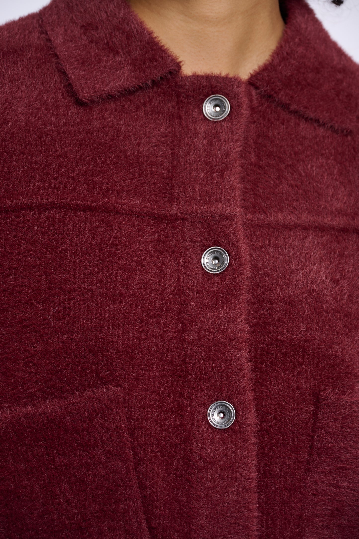 Close-up of a burgundy textured fabric with silver buttons