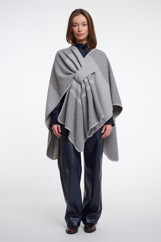 Woman wearing a gray poncho over a dark outfit on a white background