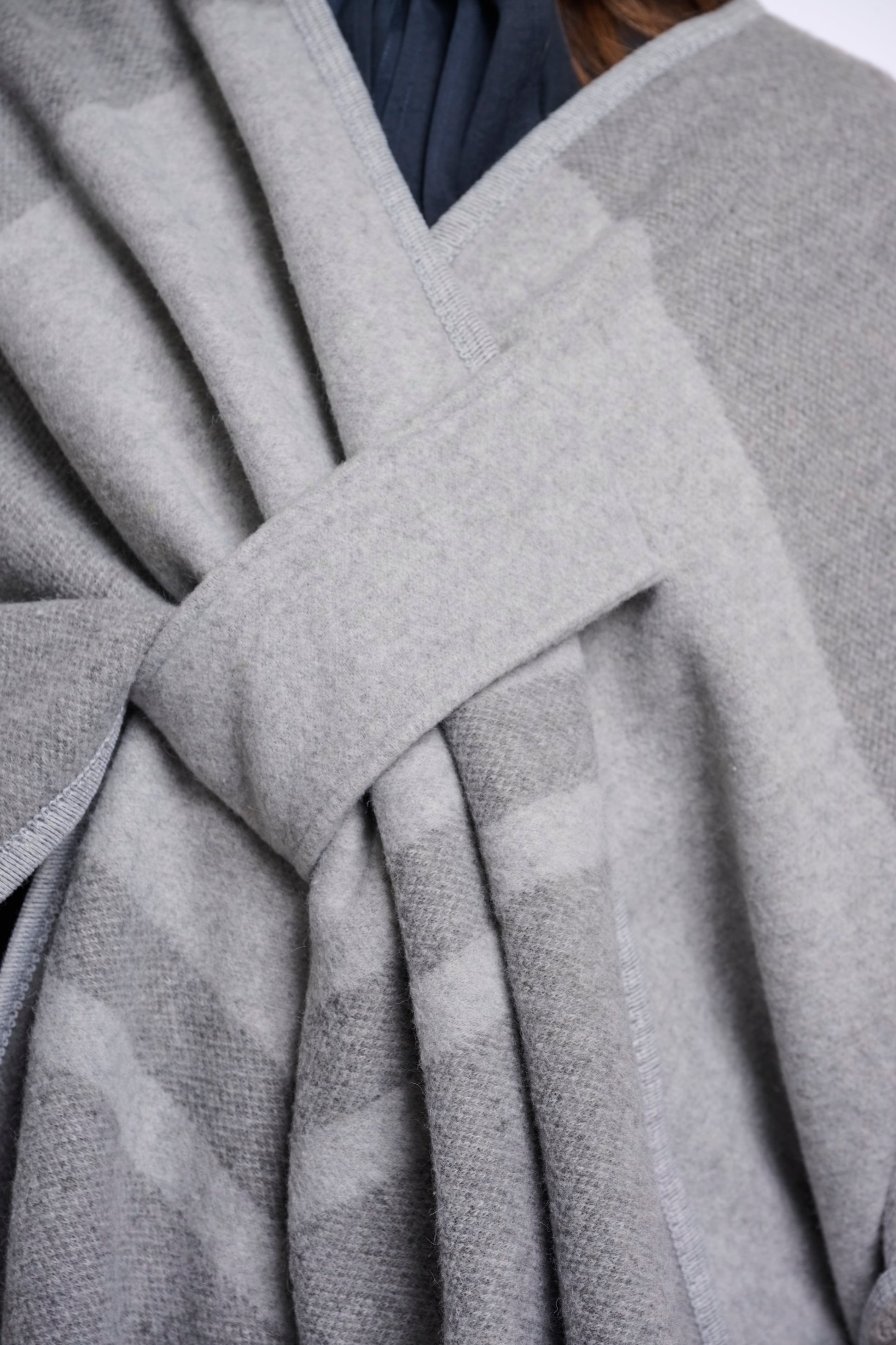 Close-up of a gray fabric with a knot, possibly from a coat or sweater.